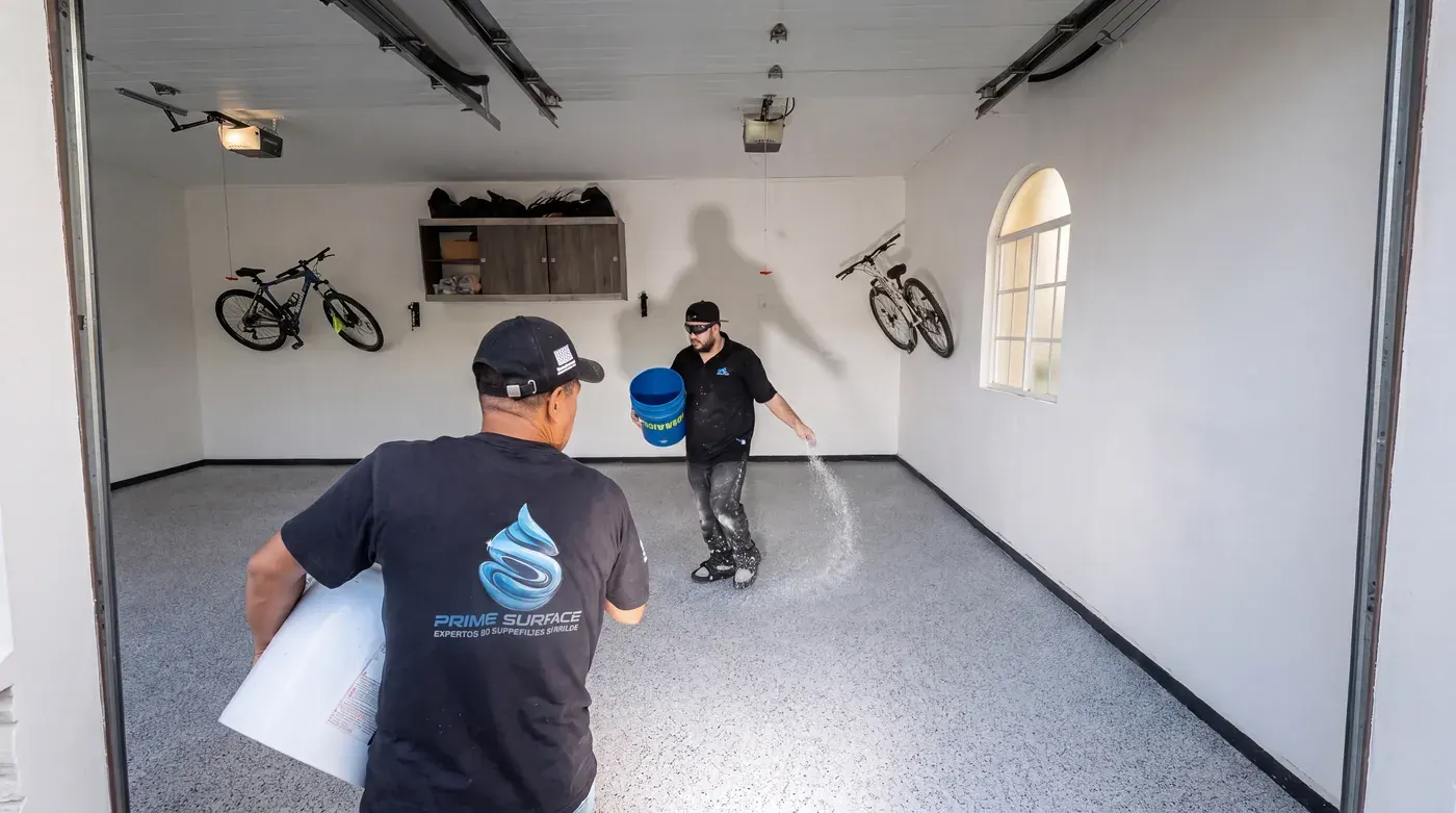 Prime Surfaces installers broadcasting flake over the epoxy base in a garage
