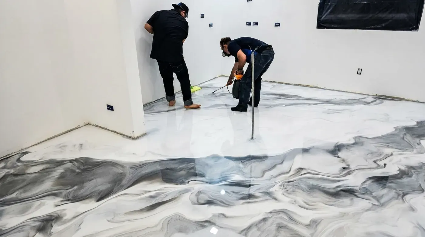 Two installers working the veining of a white and grey metallic marble floor